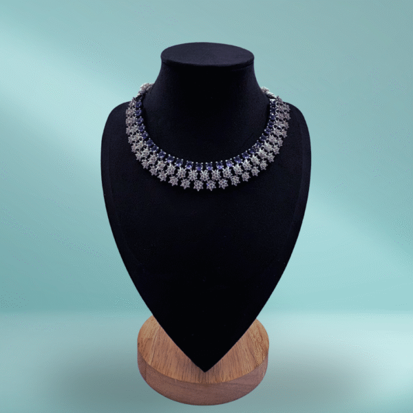 Elegant silver floral choker necklace set with detachable earrings displayed on a black velvet stand against a light grey background