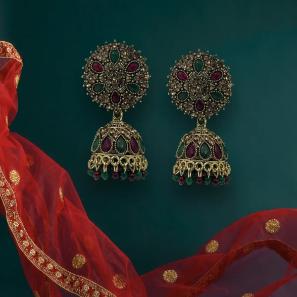 Antique gold jhumka earrings with red and green stones on white background