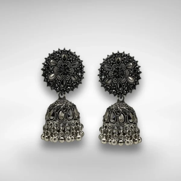 Oxidised silver jhumka earrings with floral top and dome base with hanging beads on a white background