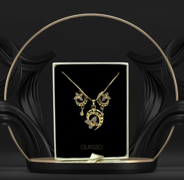Gold-plated designer pendant set with matching earrings displayed on a black jewelry stand.