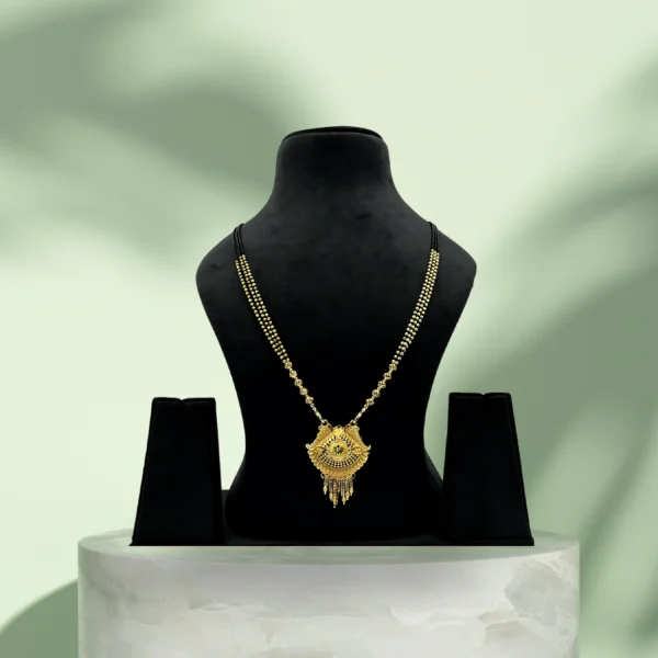 Gold-plated bridal mangalsutra with intricate pendant on black beaded chain displayed on black stand