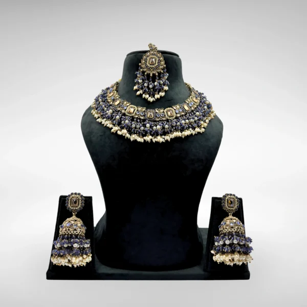 Traditional Indian bridal jewelry set with royal blue Kundan choker necklace, pearl detailing, matching earrings, and maang tikka on a white background
