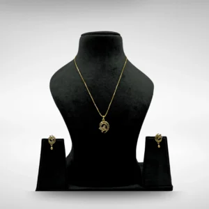 Gold-plated designer pendant set with matching earrings displayed on a black jewelry stand.