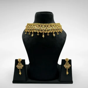 Antique gold choker necklace with red-green enamel detailing and bead drops, paired with traditional earrings, displayed on a black velvet stand